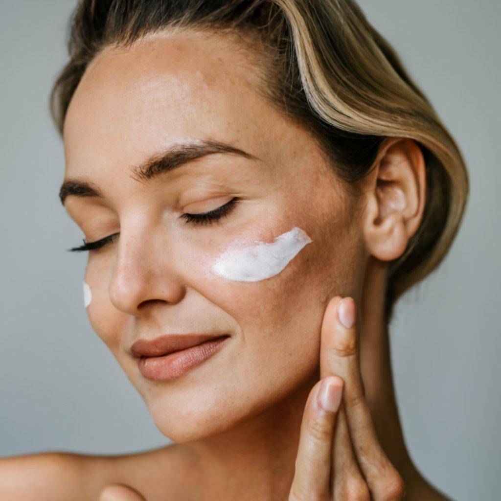 A woman smiling with face cream on her glowing skin