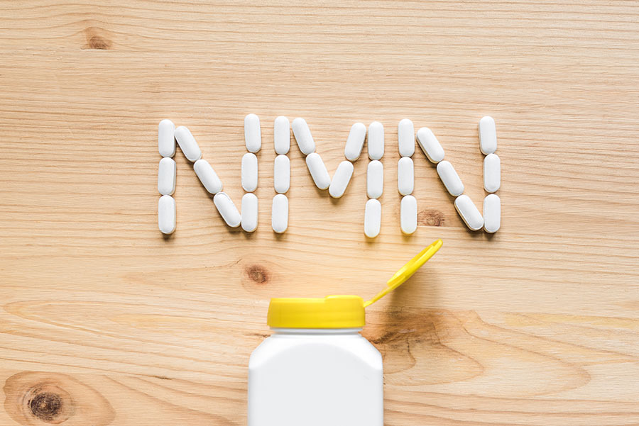 A white bottle with a yellow cover and NMN pills 