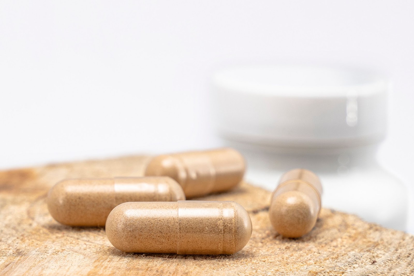 NAD+ capsules laid out on a wooden surface with a white container in the background.