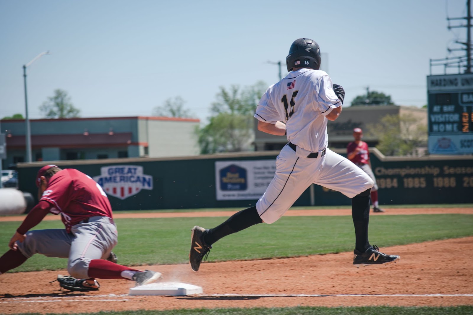 A baseball player in a white uniform sprinting to the first base