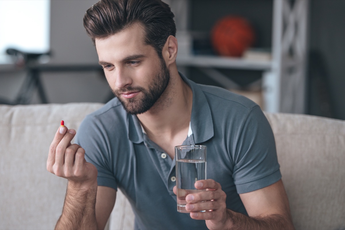 A man holding ashwagandha supplements with a half-filled glass of water