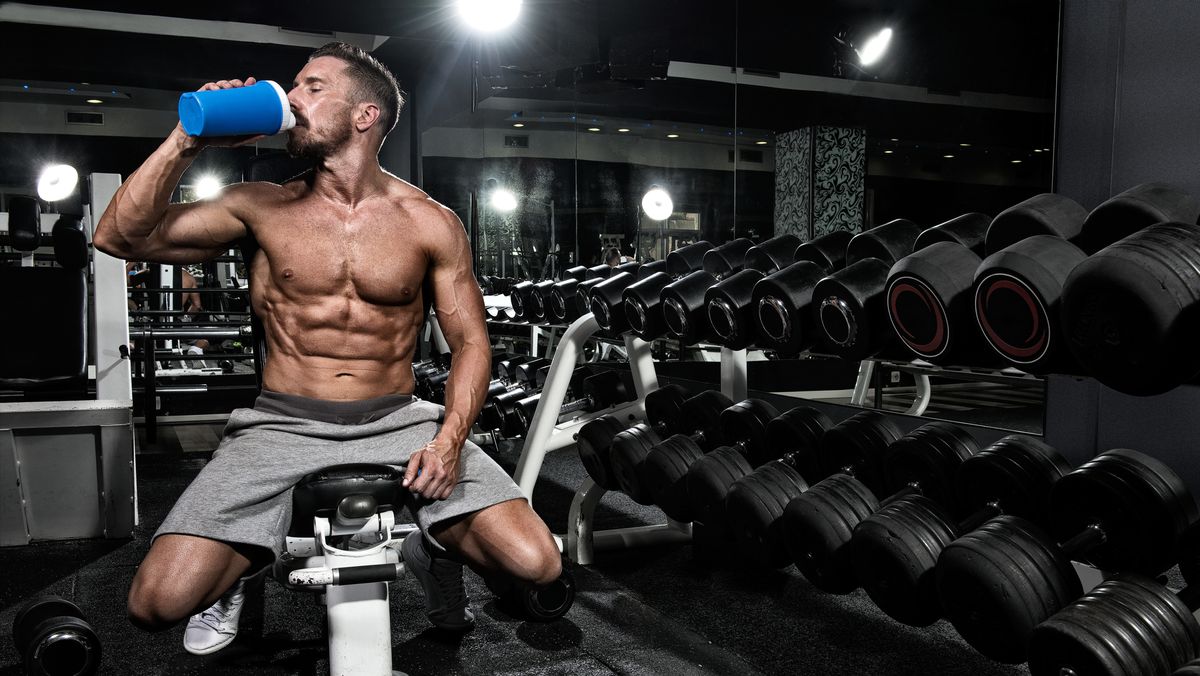 A man in the gym drinking water from a cup